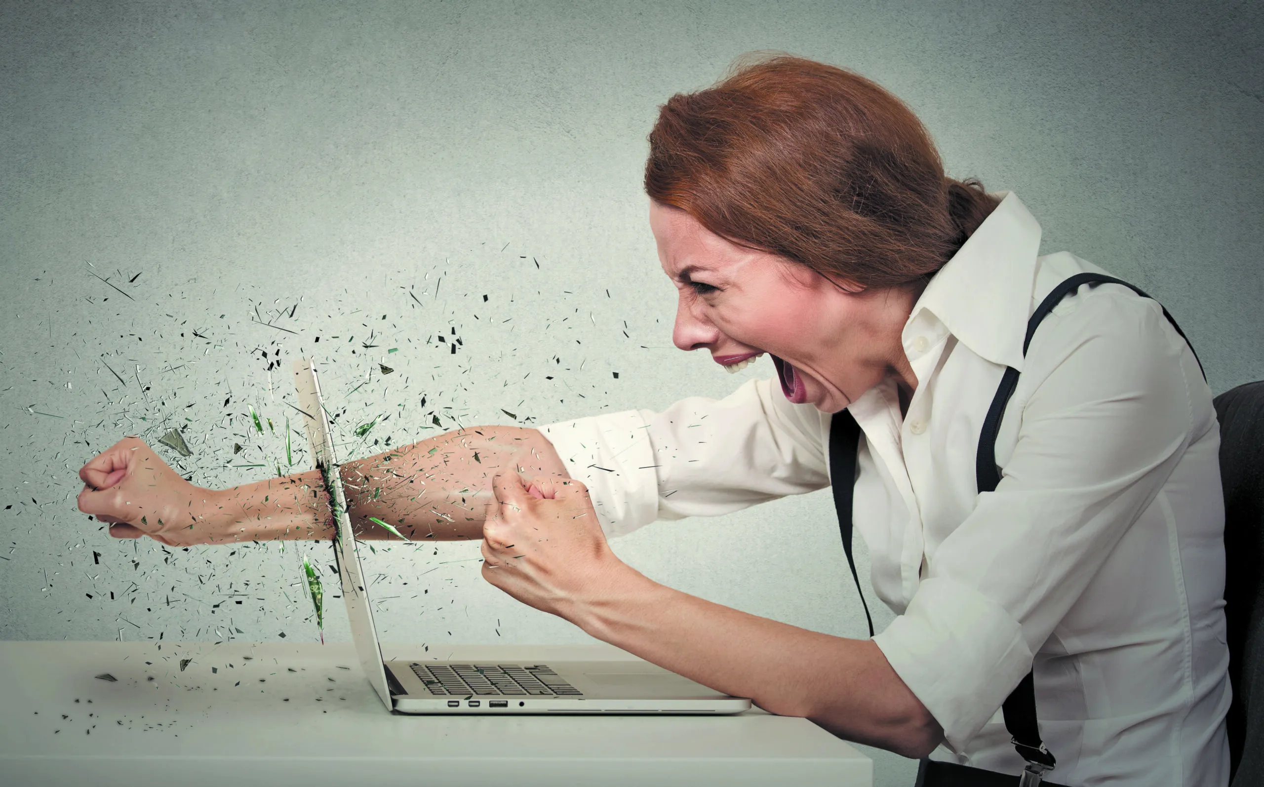 Angry,furious,businesswoman,throws,a,punch,into,computer,,screaming.,negative