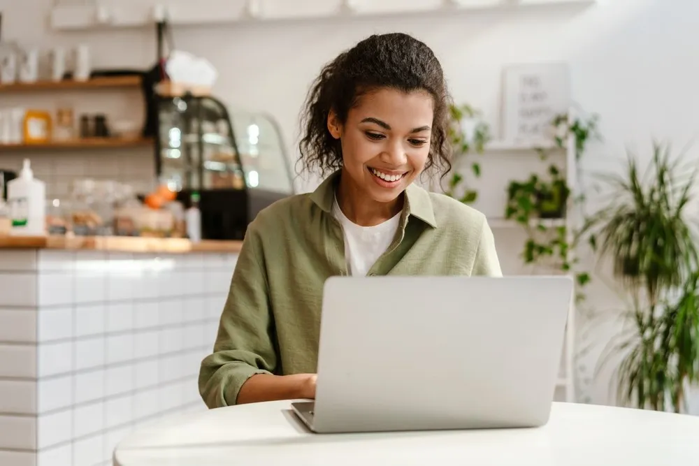 young mixed race lady working on computer At Kitchen Table